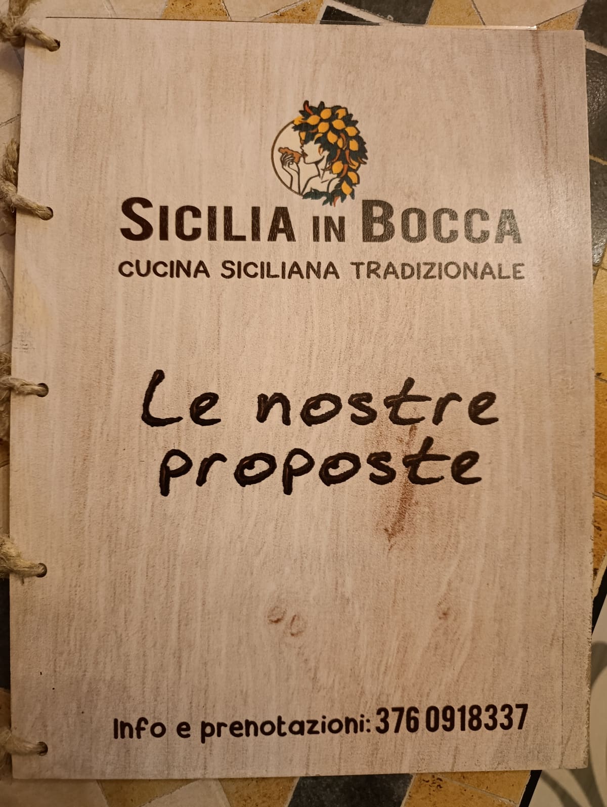La copertina del menu di Sicilia in Bocca: una tavoletta di legno rilegata con la corda, incisa con il logo e la scritta «Le nostre proposte»